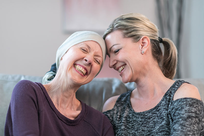 An adult child laughs with her mom who is battling cancer.